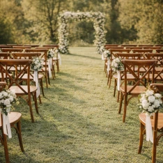 Houten crossback stoelen in een sfeervolle ceremonie opstelling voor een romantische buitenbruiloft. Klik hier om deze sfeervolle trouwstoelen direct te huren.